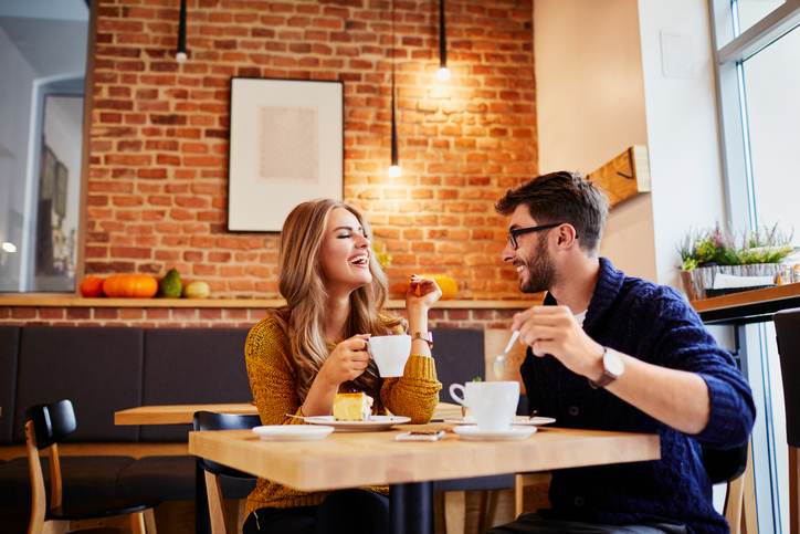 Couple of young people drinking coffee and eating cake in a stylish modern cafeteria Couple of young people drinking coffee and eating cake in a stylish modern cafeteria