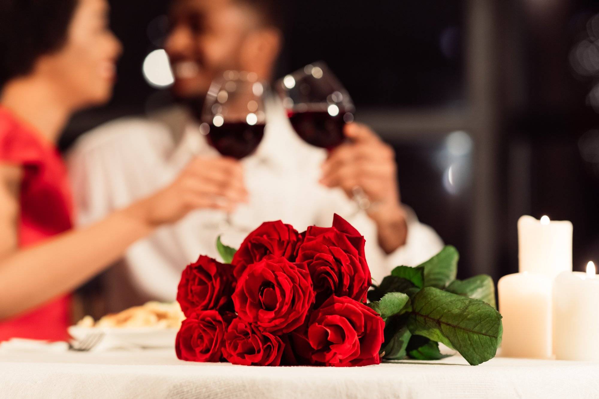 Roses Lying On Table, Unrecognizable Spouses Drinking Wine In Restaurant Roses Lying On Table, Unrecognizable Spouses Drinking Wine In Restaurant