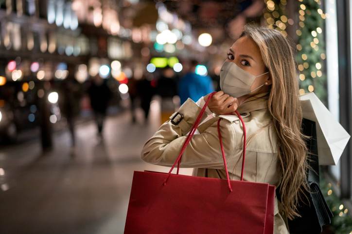 Happy woman Christmas shopping wearing a facemask Happy woman Christmas shopping wearing a facemask