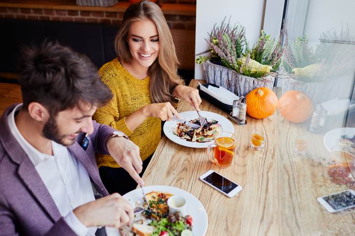 A cheerful young couple out for breakfast in a cafe before work